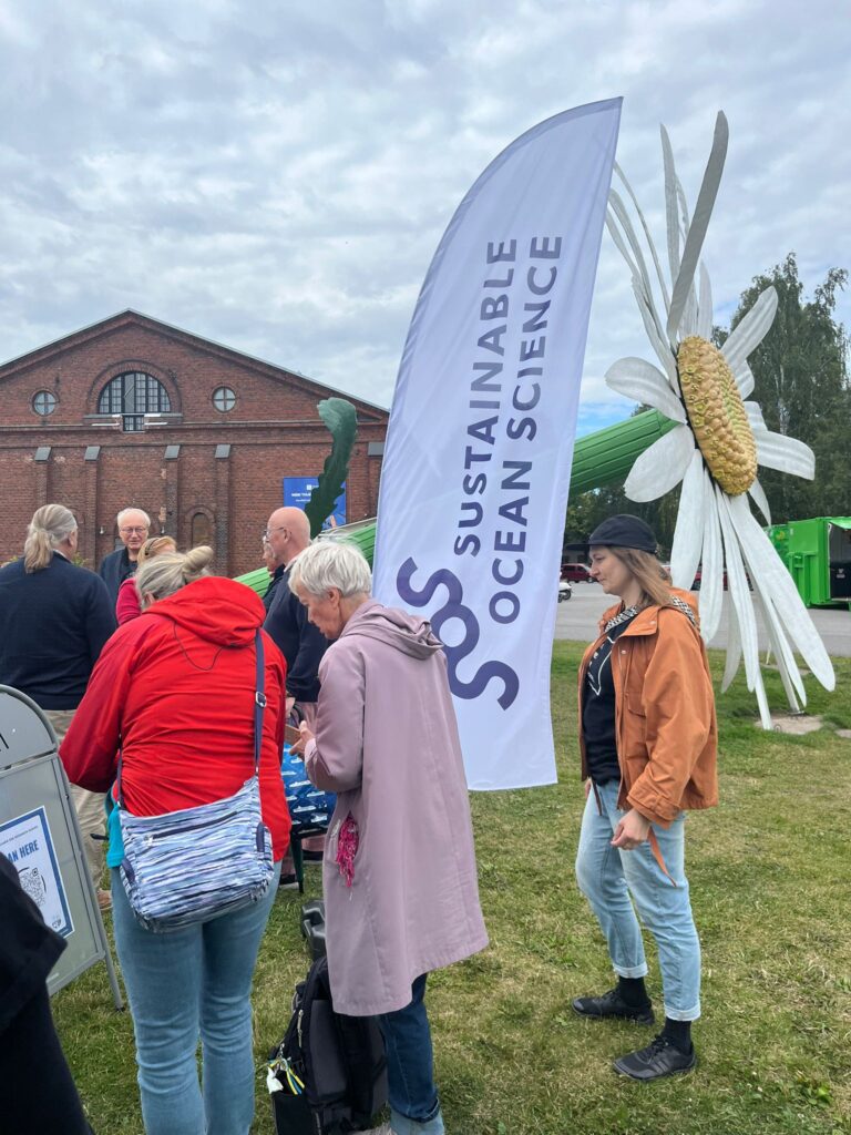 Photo of people standing outside, attending the Itämeripäivä event.