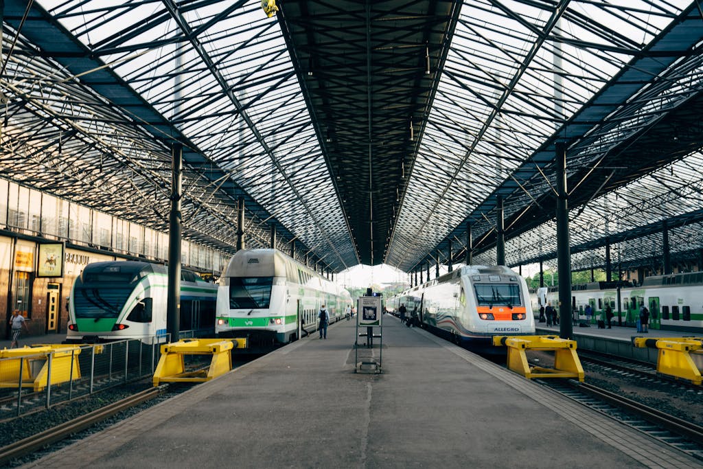 Wide-angle view of Helsinki's central train station platform with multiple trains and open roof structure.